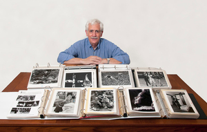 Syracuse graduate, Ron Sherman, poses with albums of his work.