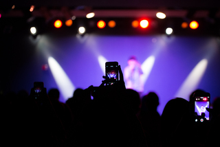 Audience members hold up phones to take a picture of the world-known freestyle rapper.