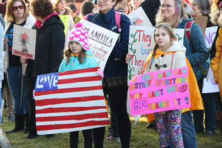 Two children hold signs. Many of the protesters at the Syracuse march included families.