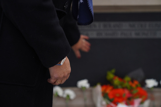 After laying a flower down by the Wall of Remembrance, a woman wearing a bracelet with the coordinates of Lockerbie touches the wall.